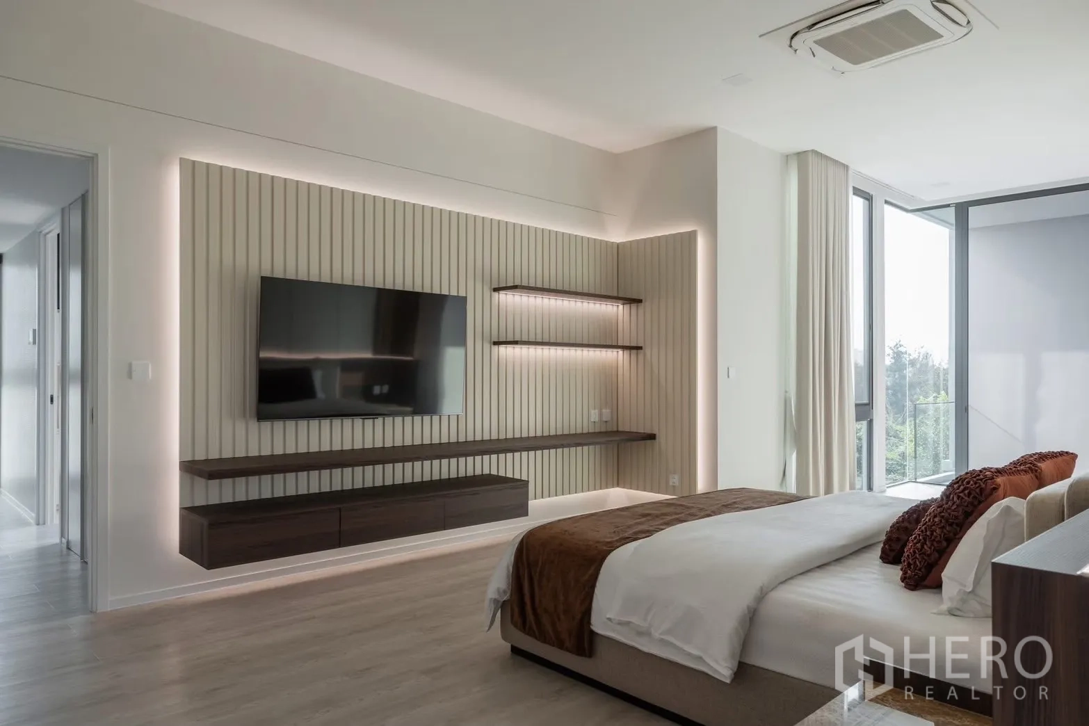 Detached House for rent in Saphan Sung, Bangkok - Master bedroom media wall with large TV, feature lighting, and wide windows.
