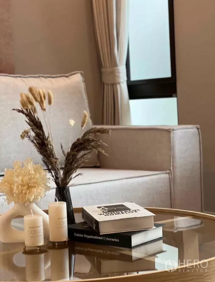 Detached House for rent in Samut Prakan - Coffee table decor with candles, dried flowers and design books in a soft-toned lounge.