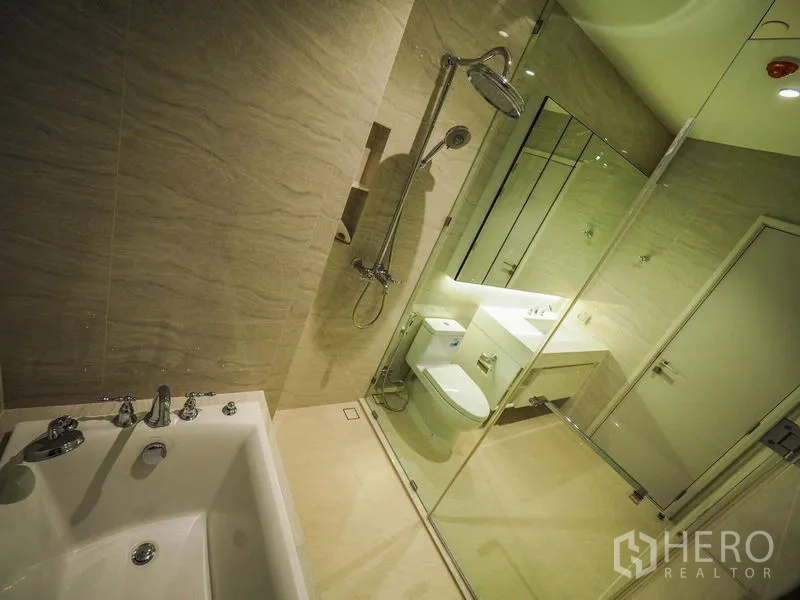คอนโด ให้เช่าในPathum Wan, Bangkok - ห้องน้ำมีอ่างอาบน้ำ ฝักบัวกั้นกระจก และเคาน์เตอร์อ่างล้างหน้าโทนสว่าง