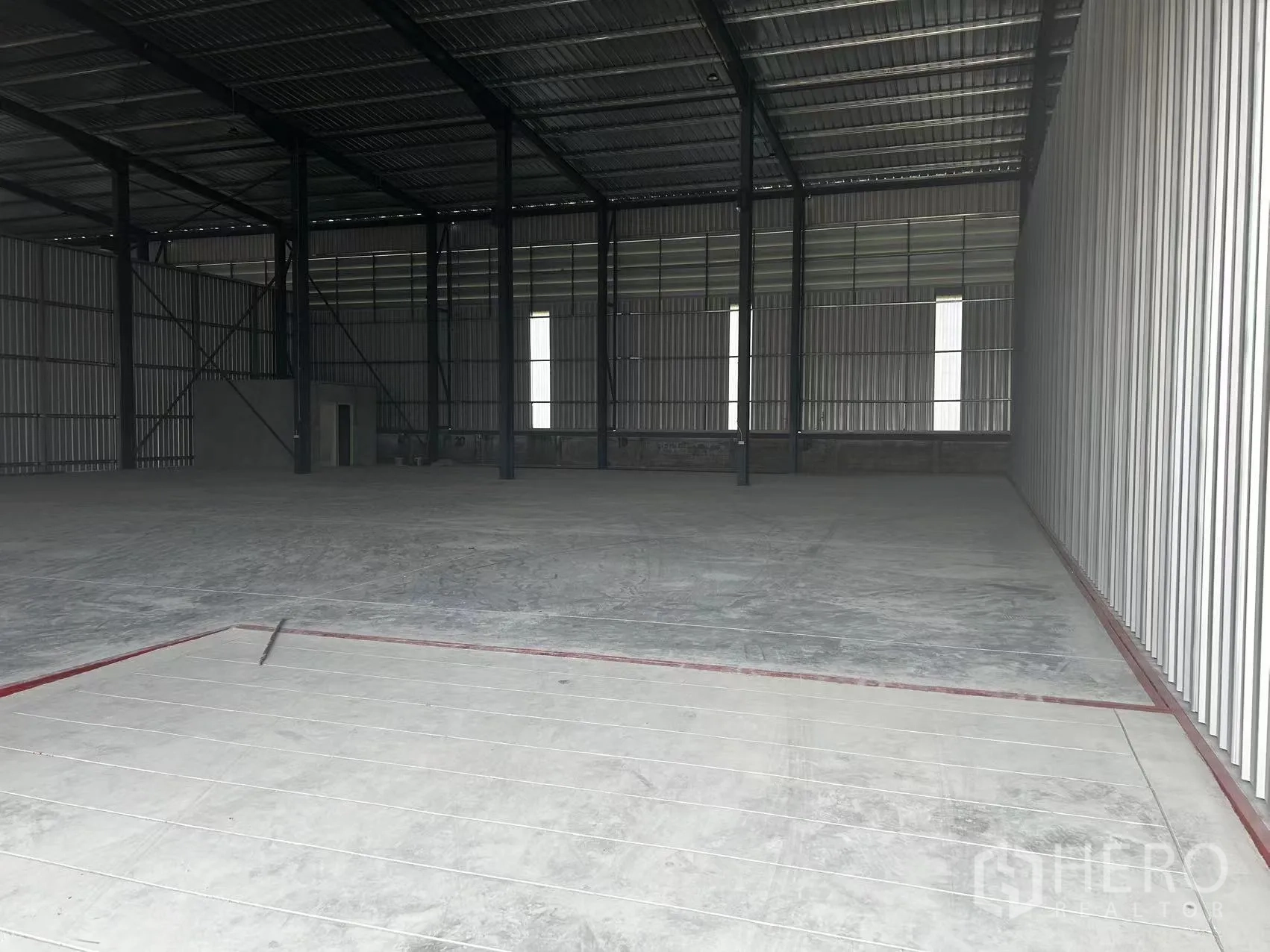 Warehouse for rent in Lam Luk Ka, Pathum Thani - View toward the loading zone inside the warehouse with structural columns and a marked apron.
