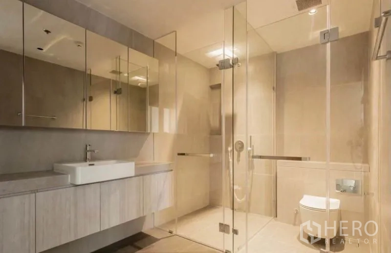 公寓 出租在Bang Rak, Bangkok - 简洁卫浴，镜面柜、大型玻璃淋浴间与悬挂式洗手台。