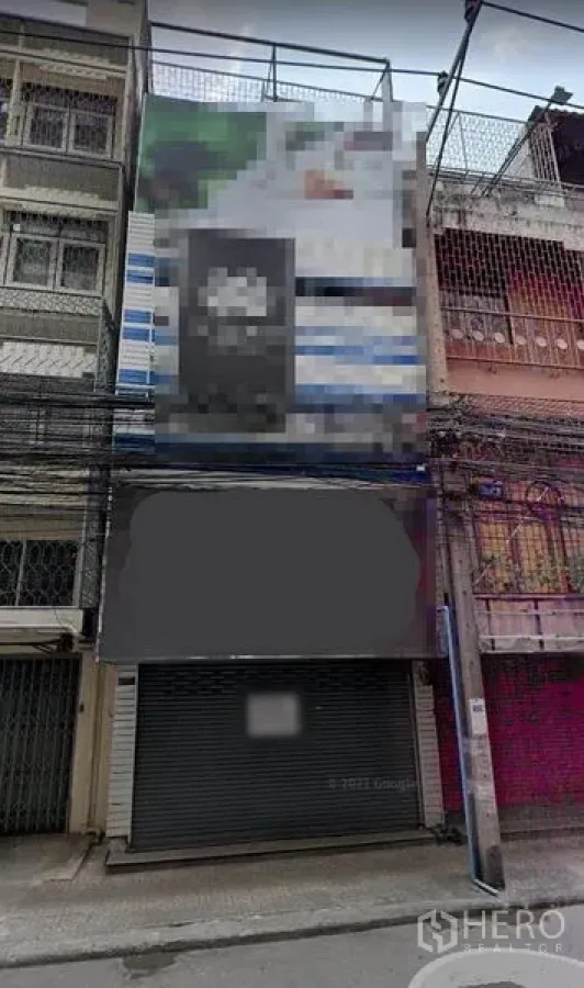 อาคารพาณิชย์ ให้เช่าในKhlong Toei, Bangkok - ด้านหน้าอาคารพาณิชย์หลายชั้นริมถนนแคบในกรุงเทพฯ พร้อมประตูม้วน ป้ายหน้าร้านโล่ง และสายสื่อสารพาดผ่าน