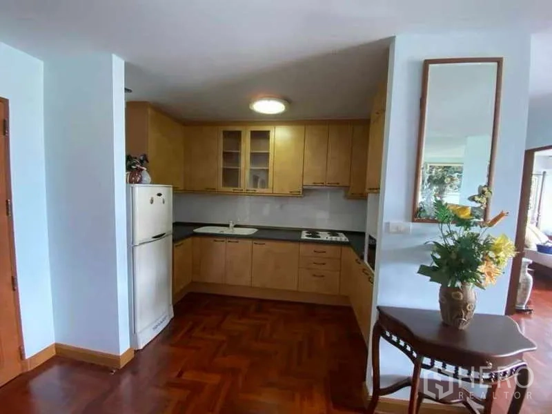 公寓 出租在Sathon, Bangkok - 公寓内U形厨房，木质柜体、冰箱与人字拼木地板。