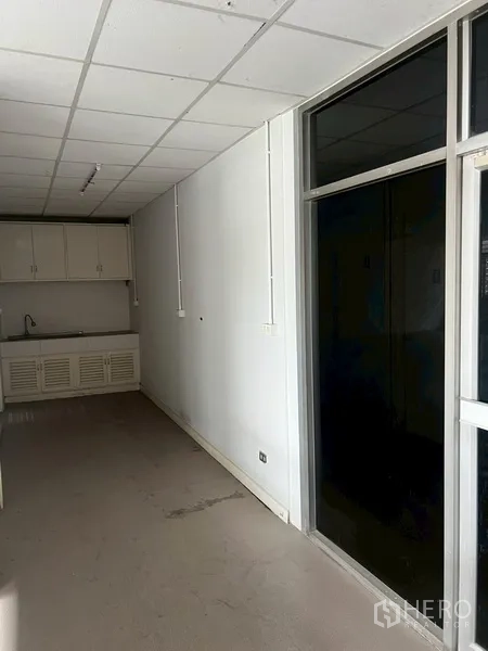 店屋 出租在Phra Khanong, Bangkok - 小茶水间，带水槽和吊柜，旁有黑色玻璃隔断。