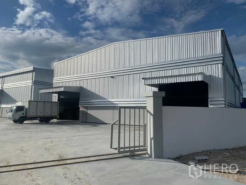 Warehouse for rent in Ban Bueng, Chon Buri - Front gate and warehouse facade with a delivery truck and covered loading entrance.