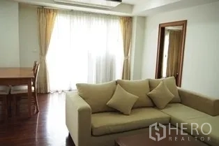 Condominium for rent in Pathum Wan, Bangkok - Sunlit lounge with sofa, large curtains and a doorway to a bedroom.