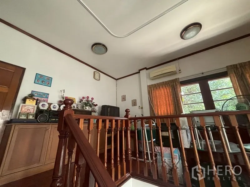独栋房屋 for sale in Suan Luang, Bangkok - 楼上小客厅，木扶手、橱柜与空调。