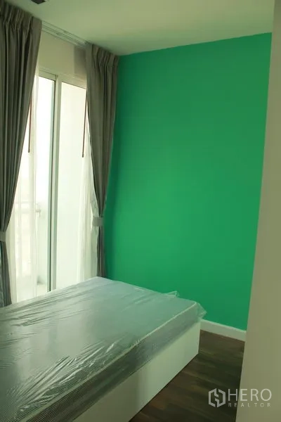 Condominium for rent or sale in Watthana, Bangkok - Third bedroom with green accent wall, bed, and balcony door with curtains.