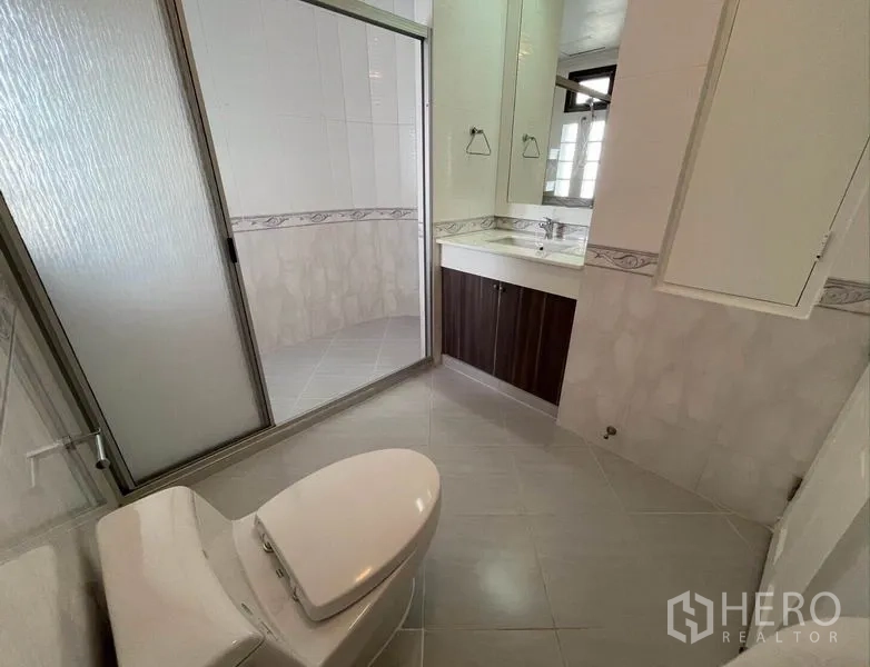 Condominium for rent in Watthana, Bangkok - Bathroom with glass-enclosed shower, mirrored vanity, and tiled walls.
