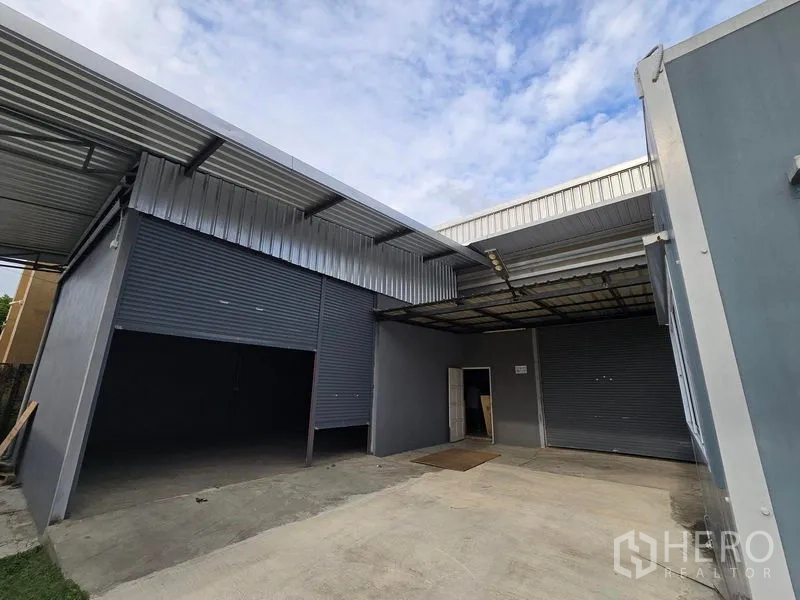 Warehouse for rent in Don Mueang, Bangkok - Dual roller shutters with canopy for loading and a concrete apron in front of the warehouse.