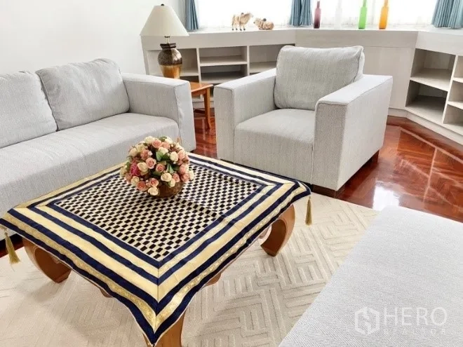 คอนโด ให้เช่าในKhlong Toei, Bangkok - ห้องนั่งเล่นสว่าง โซฟาสีเทารอบโต๊ะกาแฟไม้ ชั้นวางของบิลท์อิน และหน้าต่างมุม พื้นไม้เงา