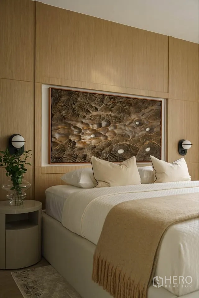 Condominium for rent in Bang Rak, Bangkok - Close-up of bedroom featuring textured artwork, bedside sconces, and neutral bedding.