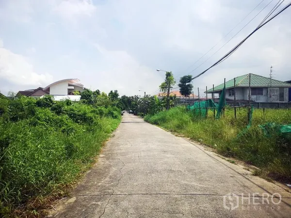 货栈 出租在Bang Khen, Bangkok - 通往仓库的混凝土小路，两侧绿植与住宅，位于Bang Khen。