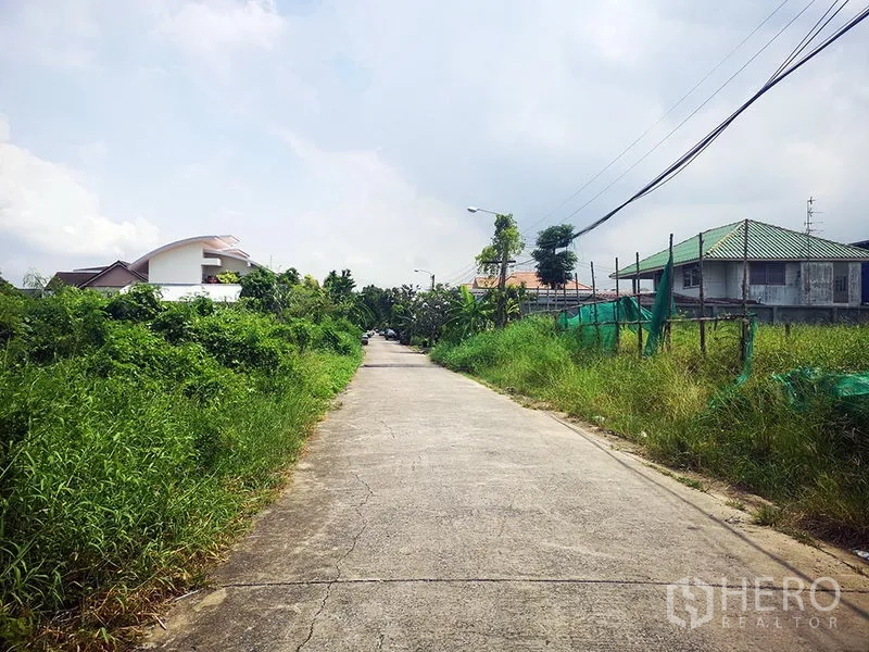 货栈 出租在Bang Khen, Bangkok - 通往仓库的混凝土小路，两侧绿植与住宅，位于Bang Khen。