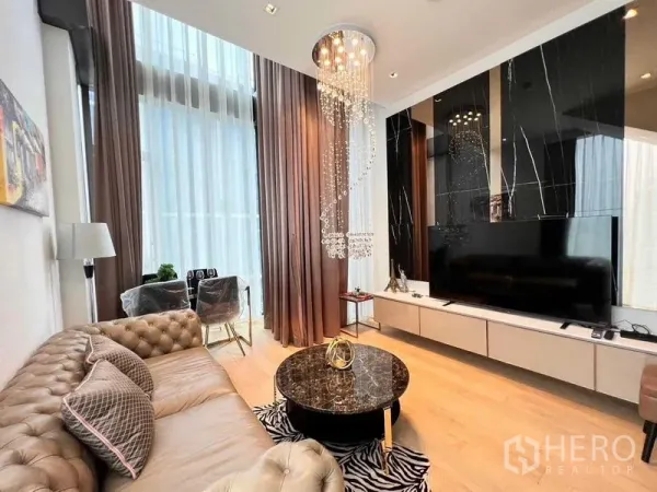 Condominium for rent - Living area with large TV on black marble feature wall and chandelier.