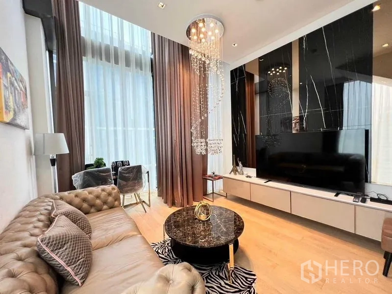 Condominium for rent - Living area with large TV on black marble feature wall and chandelier.