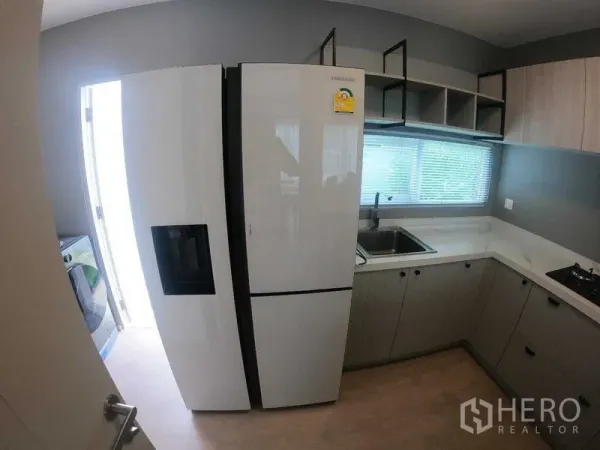 Townhouse for rent - Modern U-shaped kitchen with large refrigerator, sink below a window, and light cabinetry.