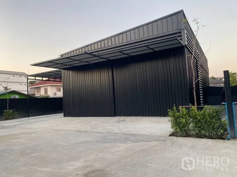 Warehouse for rent in Wang Thonglang, Bangkok - Street-side view of warehouse facade with sliding doors, deep canopy, and ample turning space.
