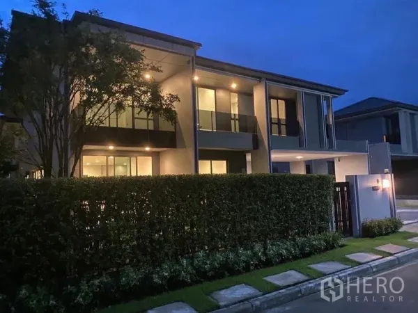 Detached House for rent in Bang Kapi, Bangkok - Night exterior of detached house with balcony, hedge and illuminated driveway.