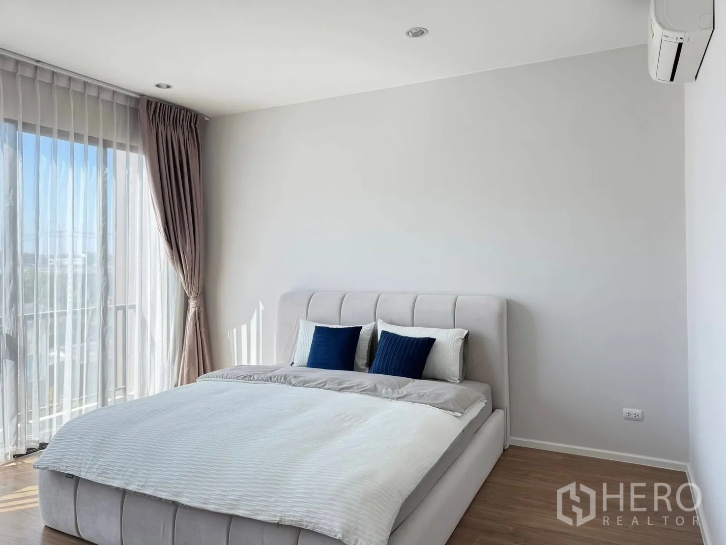 Townhouse for rent in Saphan Sung, Bangkok - Cozy bedroom with upholstered bed, floor-to-ceiling curtains and air conditioner.