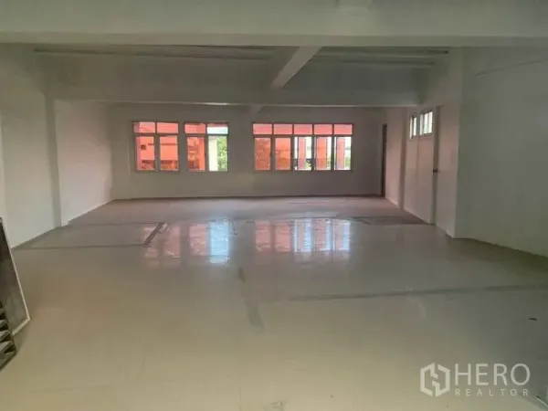 Shophouse for rent in Prawet, Bangkok - Spacious upper floor with wide windows and polished tile flooring for office layout.