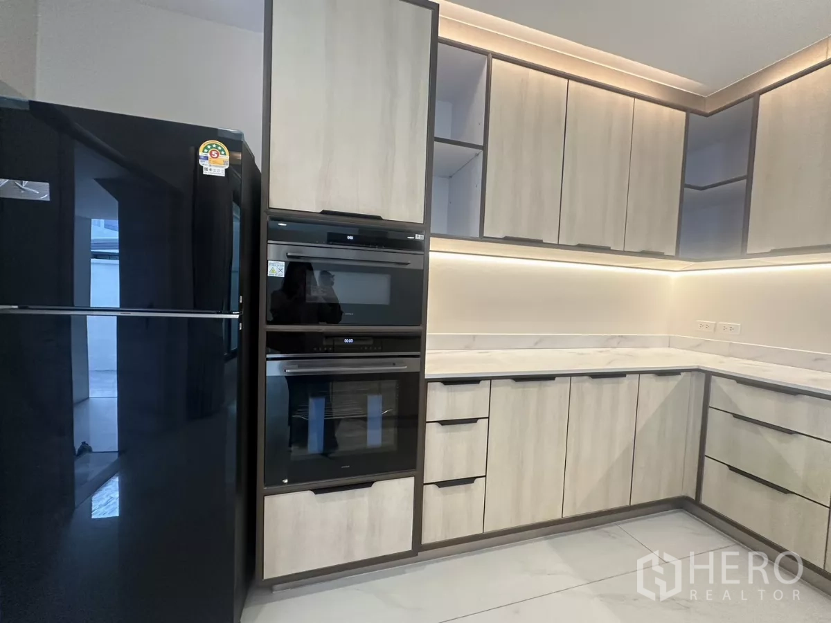 Townhouse for rent in Watthana, Bangkok - Built-in double ovens and large refrigerator within L-shaped kitchen cabinets.