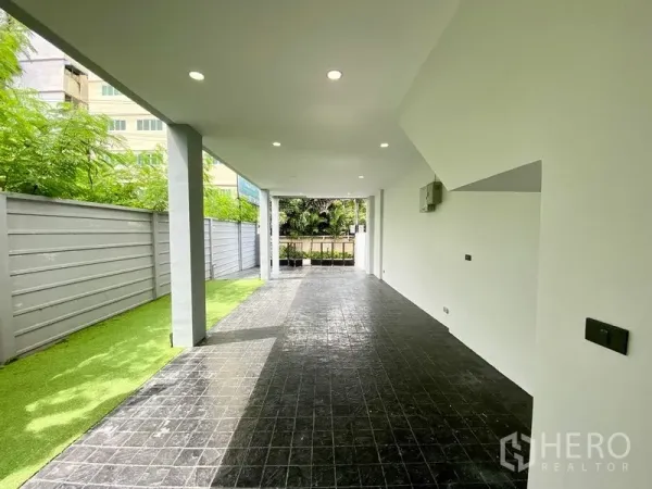 Home Office for rent or sale in Bang Na, Bangkok - Covered carport with tiled floor and a strip of artificial grass along the fence at a modern Bang Na home office.