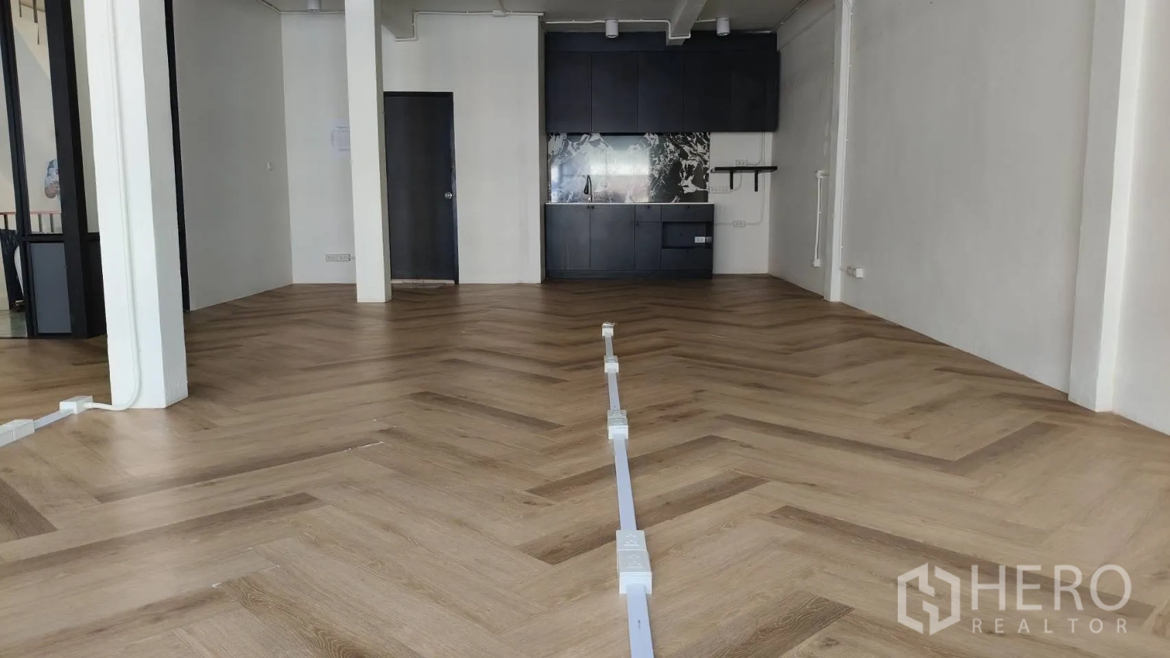 Retail Space for rent in Watthana, Bangkok - Open-plan retail area featuring herringbone flooring and a black built-in kitchenette.