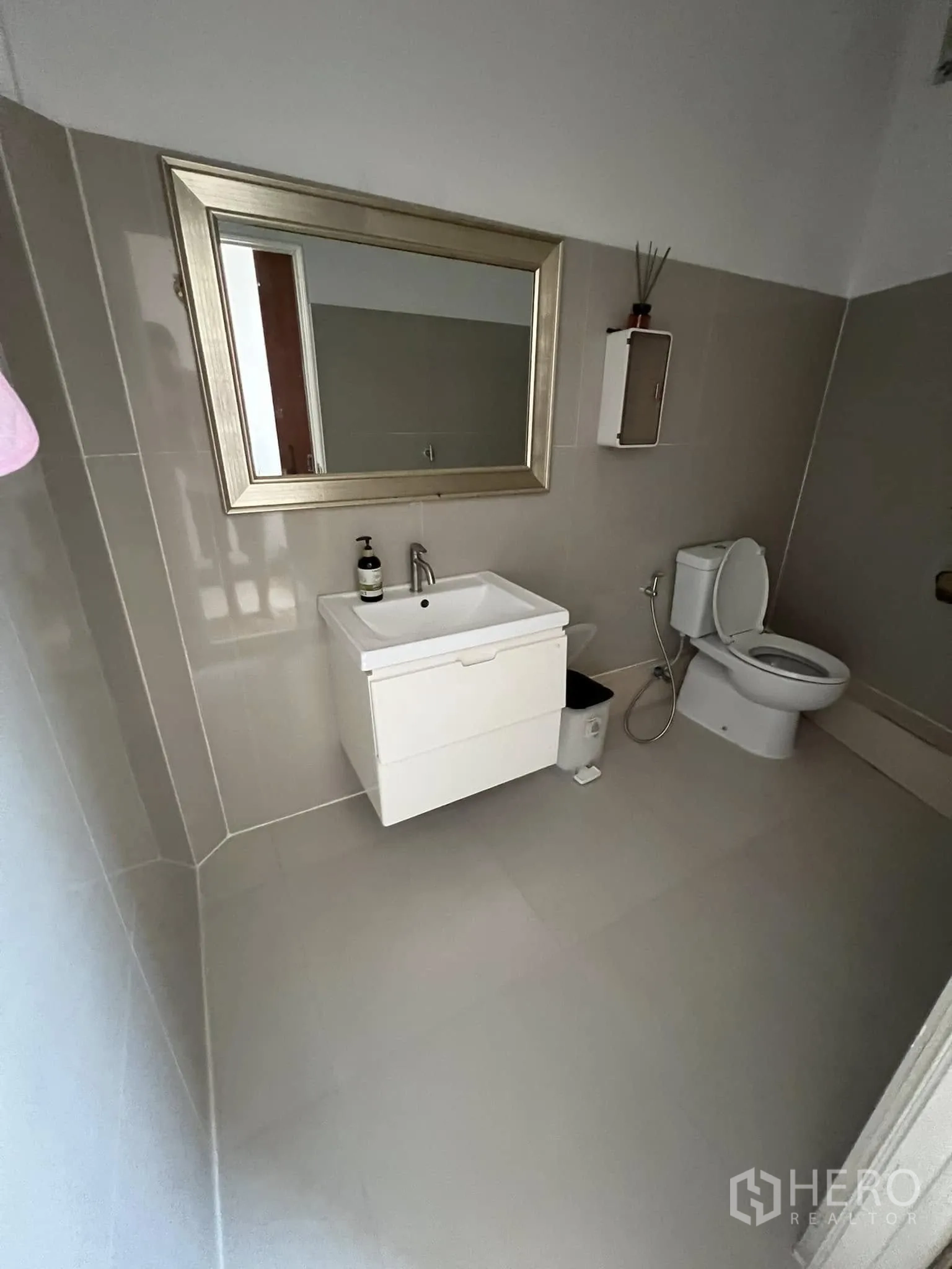 Retail Space for rent in Lat Phrao, Bangkok - Clean tiled bathroom with toilet, sink and a large framed mirror.