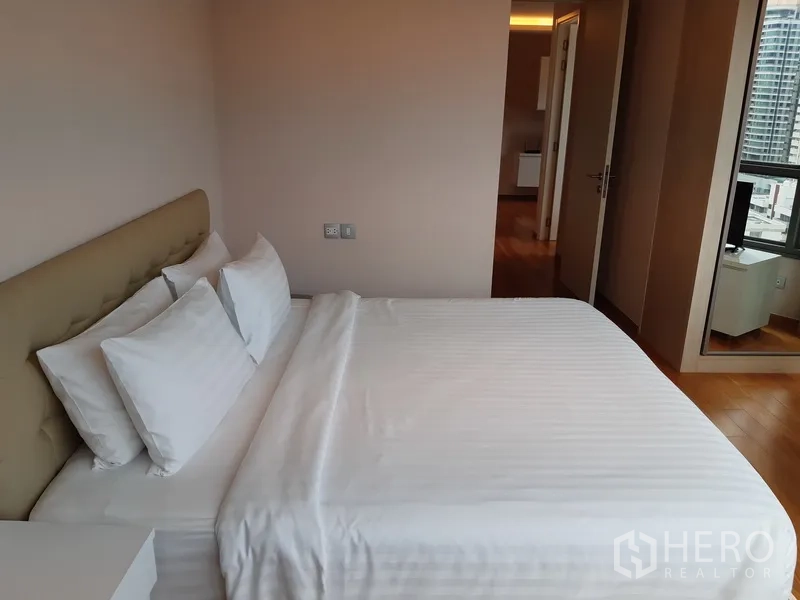 Condominium for rent in Watthana, Bangkok - Master bedroom with king bed, neutral tones and doorway to the living area.