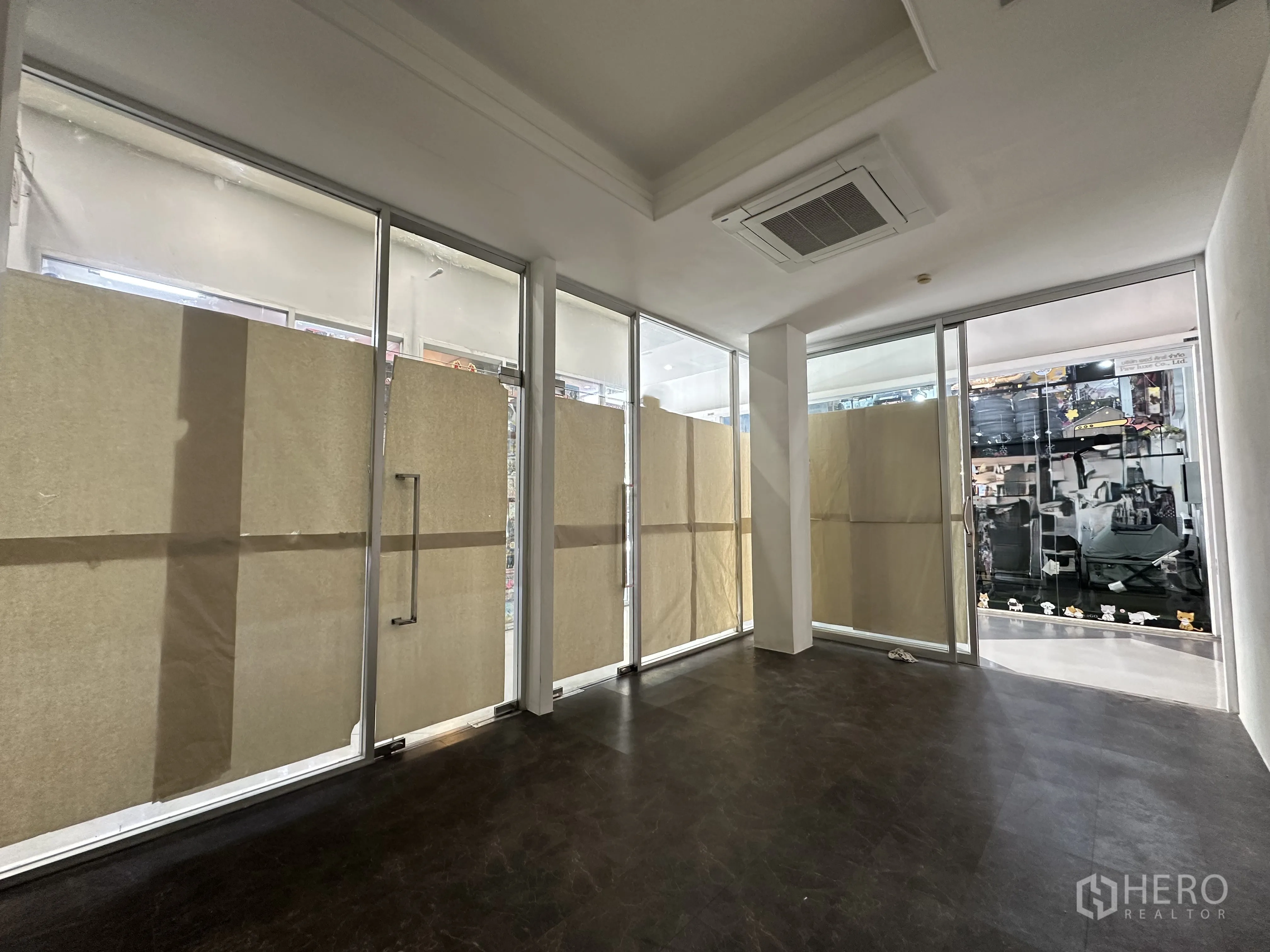 零售空间 for rent in Khlong Toei, Bangkok - 开放式零售铺面，落地玻璃门面、深色地板与吊顶嵌入式空调。
