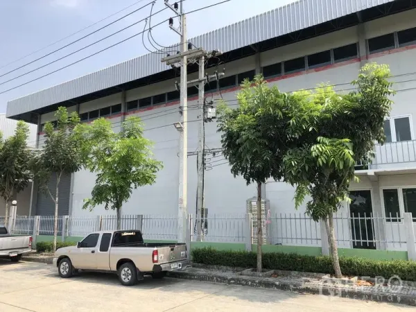 โรงงาน ให้เช่าในLam Luk Ka, Pathum Thani - ด้านข้างอาคารโรงงาน มีช่องแสงยาว รั้วรอบขอบชิด ต้นไม้และที่จอดรถริมถนน