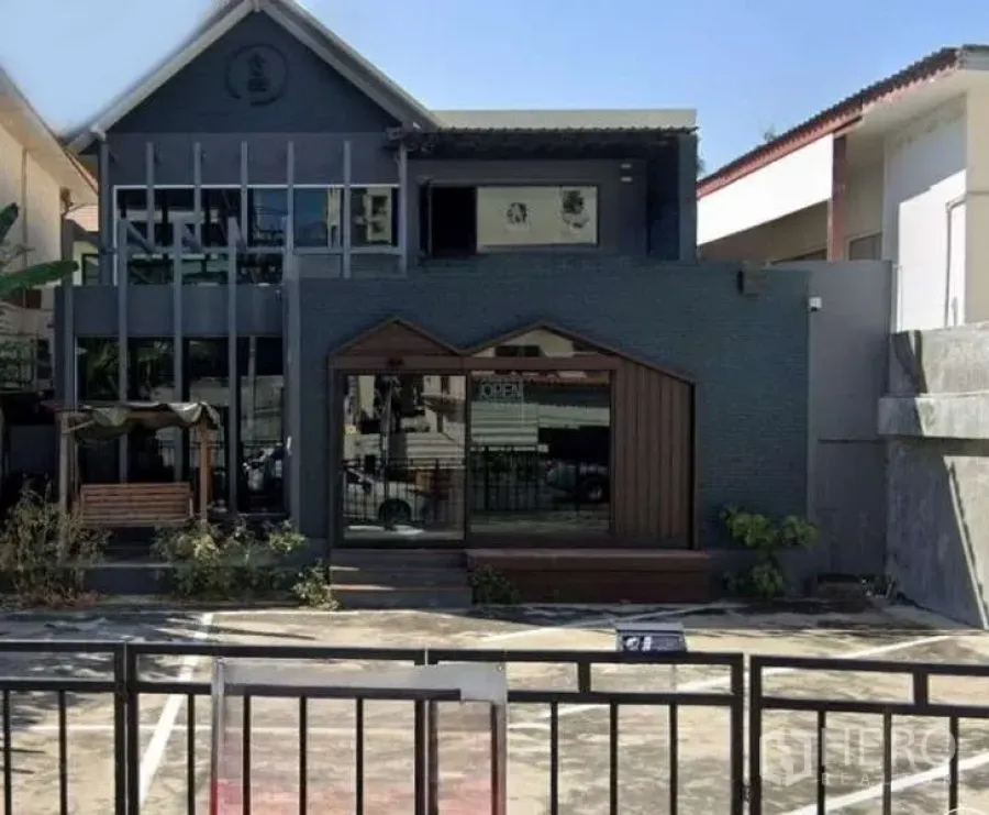 独立式住宅 出租在Watthana, Bangkok - 现代两层独栋别墅立面，大玻璃窗与前院停车位。