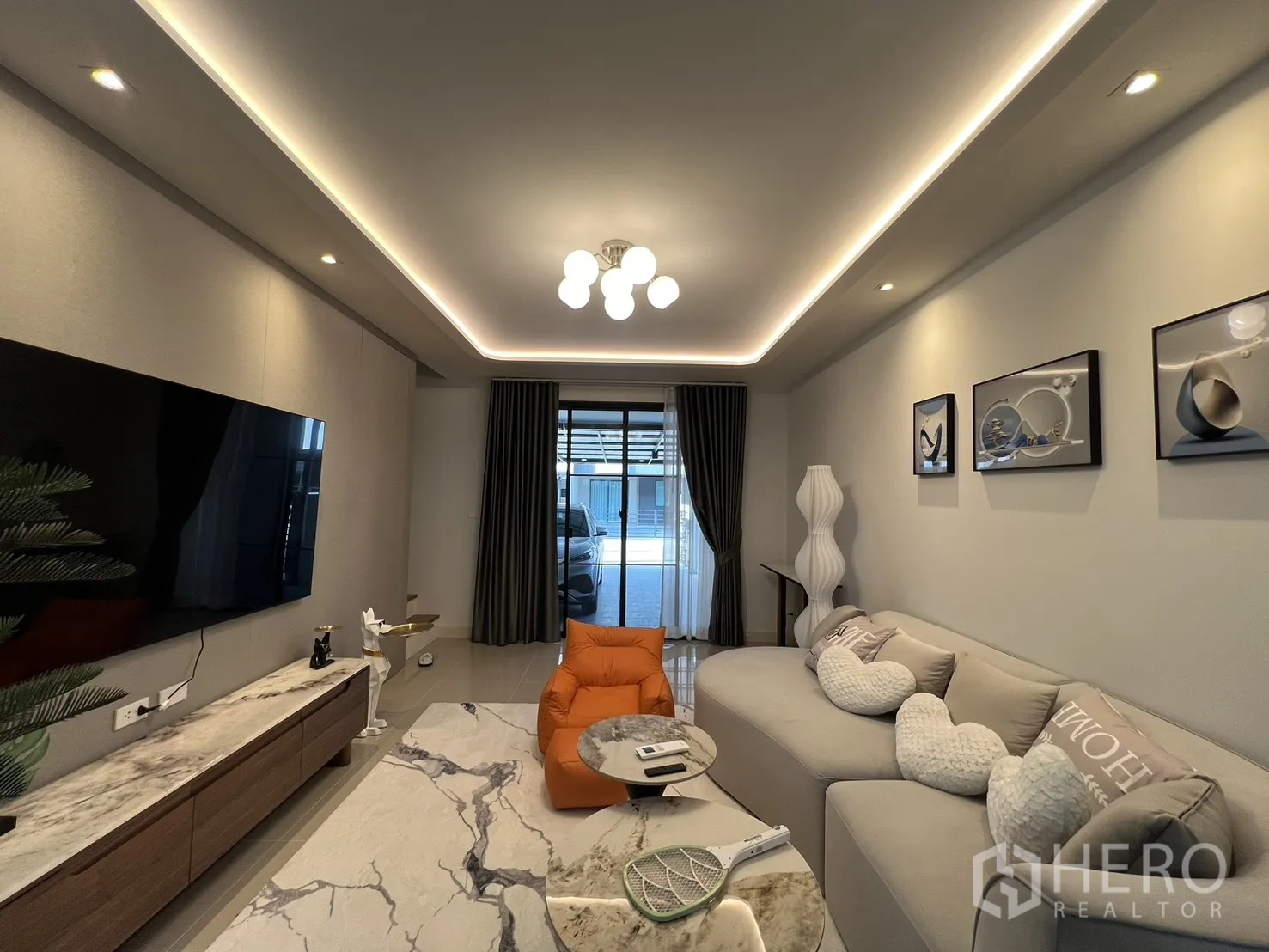 Townhouse for rent in Bang Phli, Samut Prakan - Symmetrical living room with mounted TV, artwork and a marble-top media console.