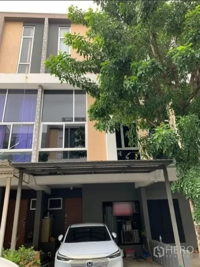 联排别墅 出租在Khan Na Yao, Bangkok - 三层联排外立面，带遮雨车棚与大树。