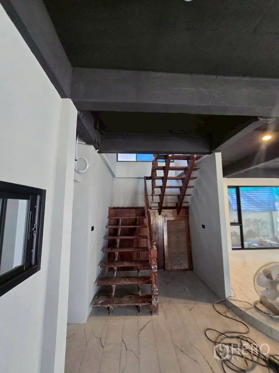 Detached House for rent in Phra Khanong, Bangkok - Wooden staircase with white walls, tiled floor, and black exposed ceiling beams.