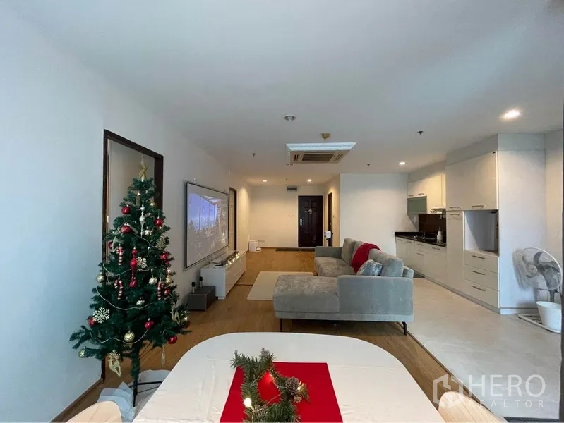 คอนโด ให้เช่าหรือขายในWatthana, Bangkok - ห้องนั่งเล่นแบบโอเพนแพลนในคอนโดวัฒนา กรุงเทพฯ พร้อมโซฟาเข้ามุม ผนังโปรเจคเตอร์ และครัวบิลท์อิน