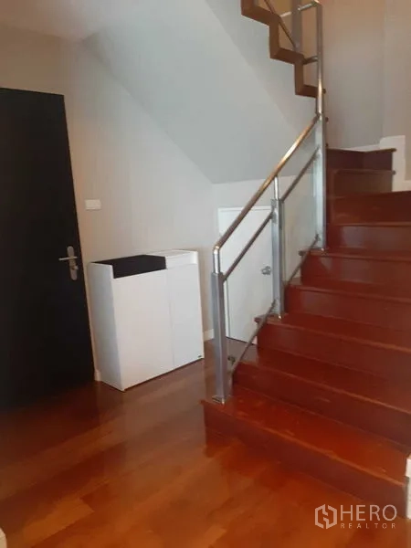 Condominium for rent or sale in Huai Khwang, Bangkok - Internal wooden staircase with metal handrail inside the duplex condo.