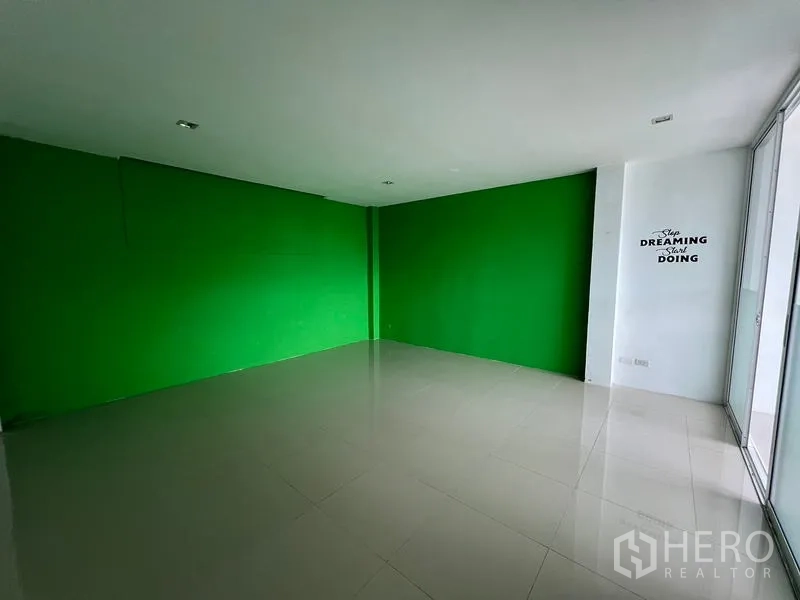 Warehouse for rent in Bang Phli, Samut Prakan - Studio room with green feature wall and glass partition over tiled flooring.