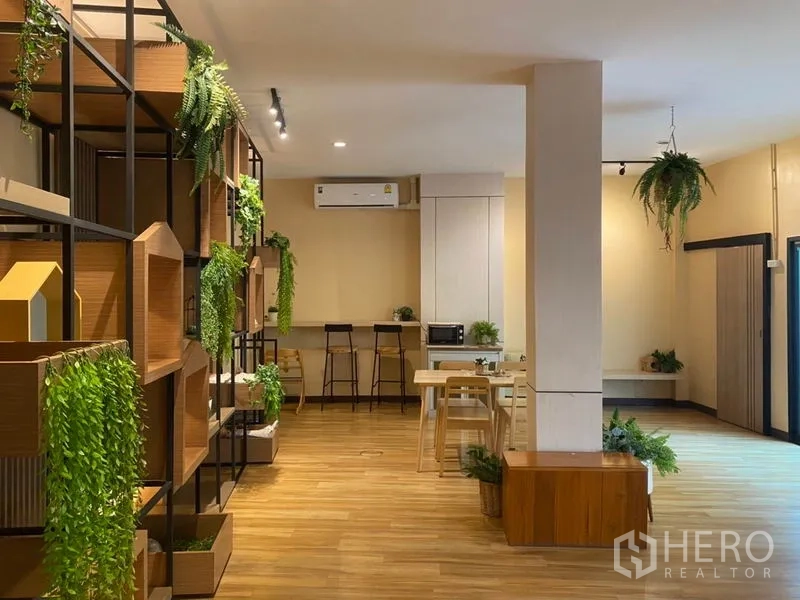 零售空间 出租在Khlong Toei, Bangkok - 商铺内带装饰展示架与绿植，吧台高脚凳，温暖木地面。