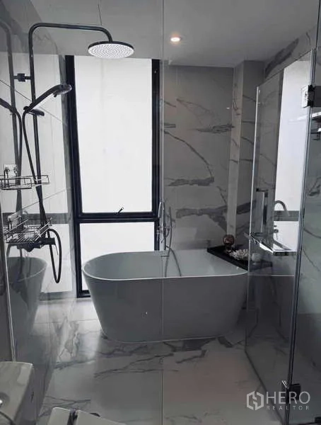 Condominium for rent in Khlong Toei, Bangkok - Marble bathroom with freestanding tub, rain shower and large window.