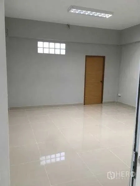 Warehouse for rent in Mueang Samut Prakan, Samut Prakan - Bright office room with glossy tile flooring, window, and wooden door.
