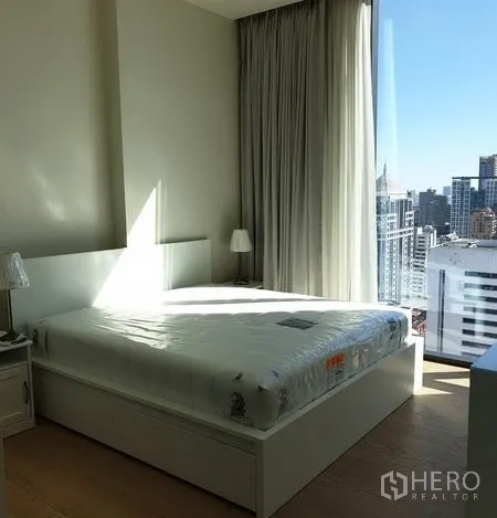 Condominium for rent in Pathum Wan, Bangkok - Sunlit master bedroom with large bed, tall windows and Bangkok skyline vista.
