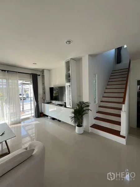 บ้าน ให้เช่าในBang Kapi, Bangkok - มุมห้องนั่งเล่นพร้อมผนังทีวีและบันไดขึ้นชั้นบน