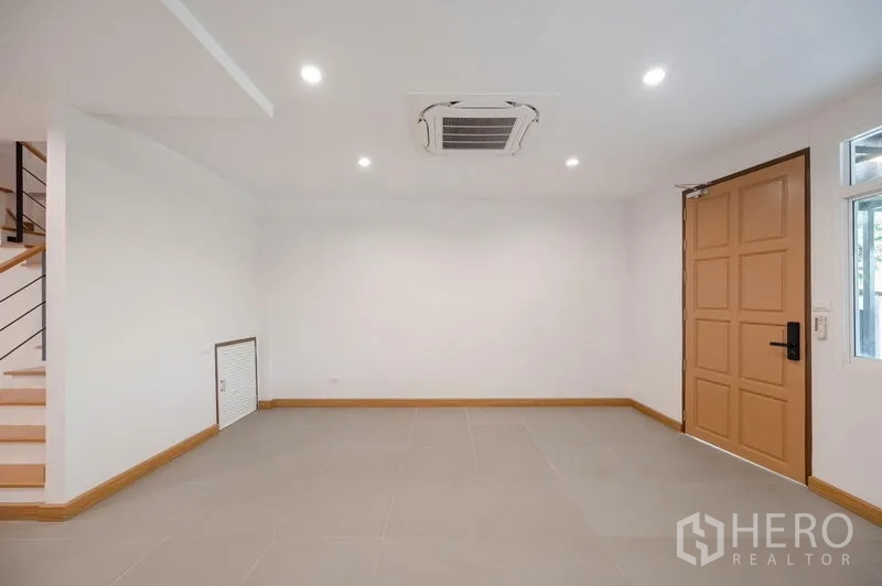 ทาวน์เฮาส์ ขายในLat Phrao, Bangkok - โถงทางเข้าและพื้นที่นั่งเล่นพร้อมประตูไม้และแอร์ฝังฝ้า