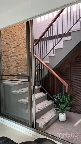 公寓 出租 - 室内楼梯，金属栏杆与石质装饰墙，玻璃门旁摆放绿植