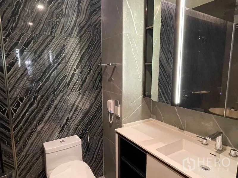 Condominium for rent - Primary bathroom with lighted mirror, wide vanity and marble accent wall.
