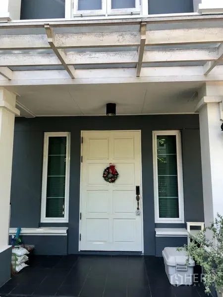 Detached House for rent in Bang Kapi, Bangkok - Close-up of the front porch with a white entry door beneath a pergola-style canopy.