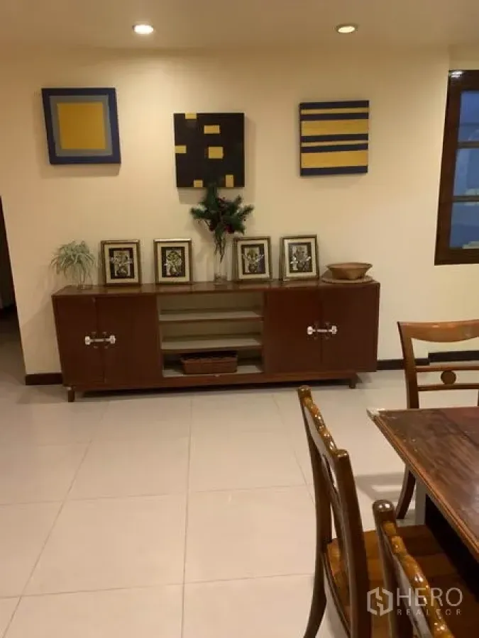 ทาวน์เฮาส์ ให้เช่าหรือขายในPhra Khanong, Bangkok - ตู้ไม้พร้อมกรอบรูปและงานศิลป์ลายเรขาคณิตในห้องปูกระเบื้องสว่าง