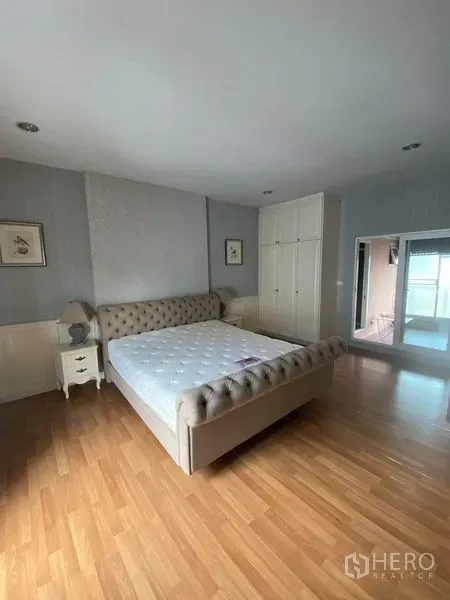 Townhouse for rent in Wang Thonglang, Bangkok - Spacious master bedroom with tufted bed, wardrobes and wood flooring.